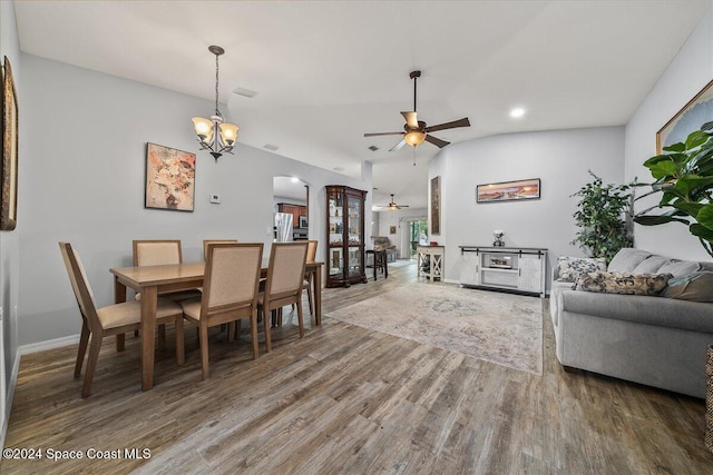 dining area featuring vaulted ceiling, wood-type flooring, and ceiling fan with notable chandelier