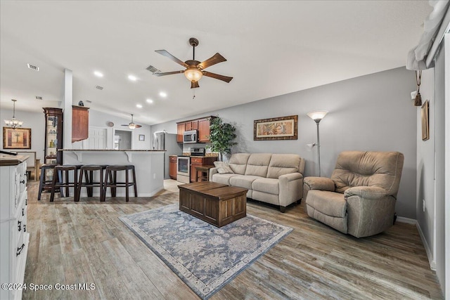 living room with vaulted ceiling, ceiling fan, and light wood-type flooring