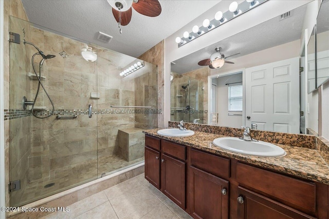 bathroom with ceiling fan, vanity, a textured ceiling, tile patterned floors, and walk in shower