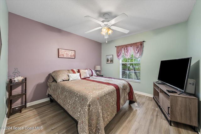 bedroom featuring a textured ceiling, ceiling fan, and light wood-type flooring