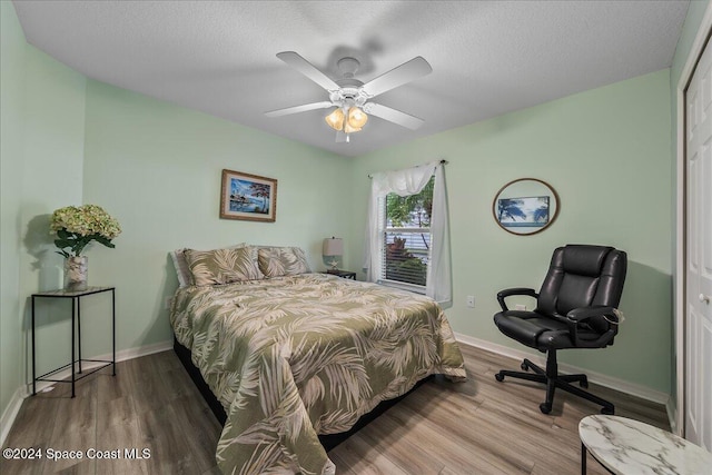 bedroom with hardwood / wood-style flooring, ceiling fan, and a textured ceiling