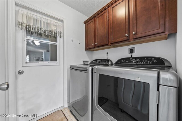 washroom with cabinets, independent washer and dryer, a textured ceiling, and light tile patterned floors