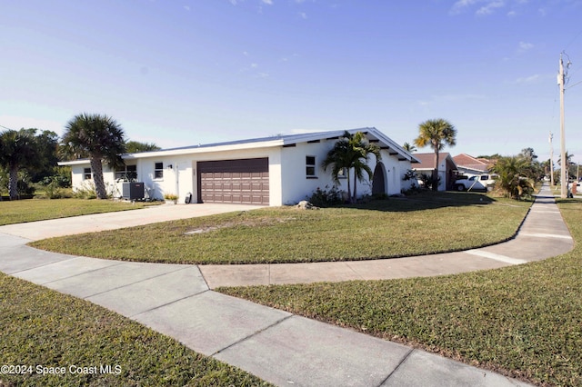 view of front of property featuring a front yard, central AC, and a garage