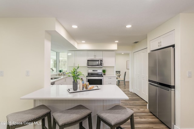 kitchen with a center island, dark wood-type flooring, stainless steel appliances, a breakfast bar area, and white cabinets