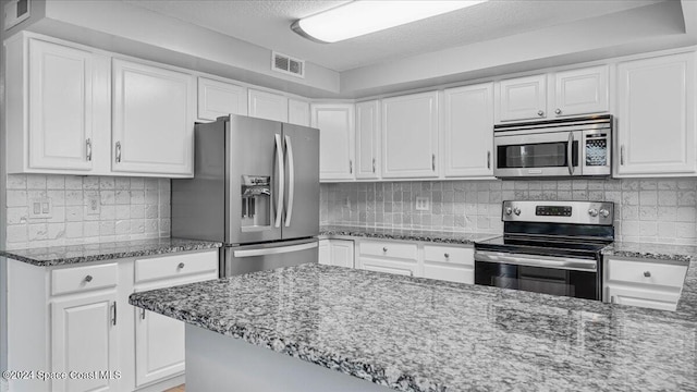 kitchen featuring tasteful backsplash, white cabinets, stainless steel appliances, and stone countertops