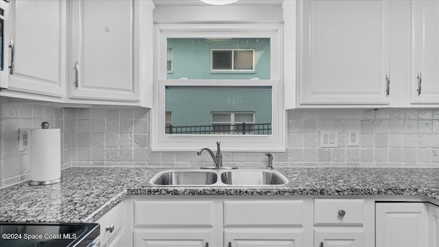 kitchen with white cabinets, tasteful backsplash, stone counters, and sink