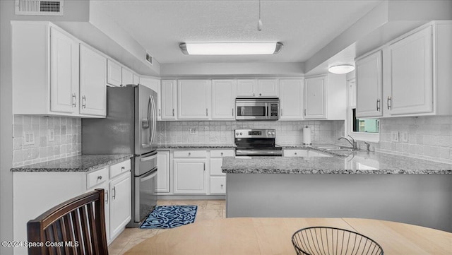 kitchen with backsplash, white cabinets, sink, light stone countertops, and appliances with stainless steel finishes