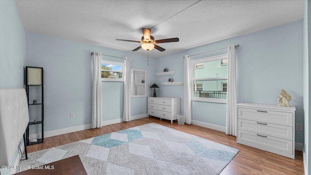 bedroom with a textured ceiling, light hardwood / wood-style floors, and ceiling fan