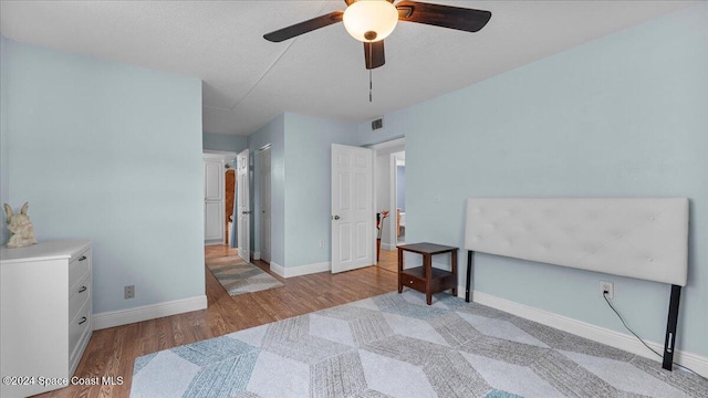 bedroom with a textured ceiling, light hardwood / wood-style floors, and ceiling fan