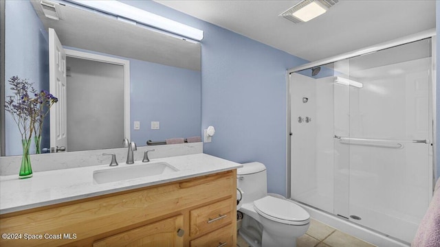 bathroom featuring tile patterned flooring, vanity, an enclosed shower, and toilet