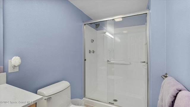 bathroom with vanity, toilet, and a shower with door