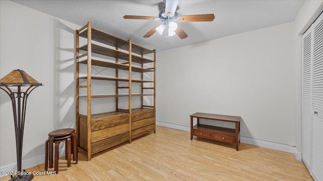 bedroom with a textured ceiling, a closet, light hardwood / wood-style floors, and ceiling fan