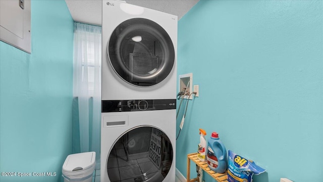 laundry room with a textured ceiling and stacked washer and clothes dryer