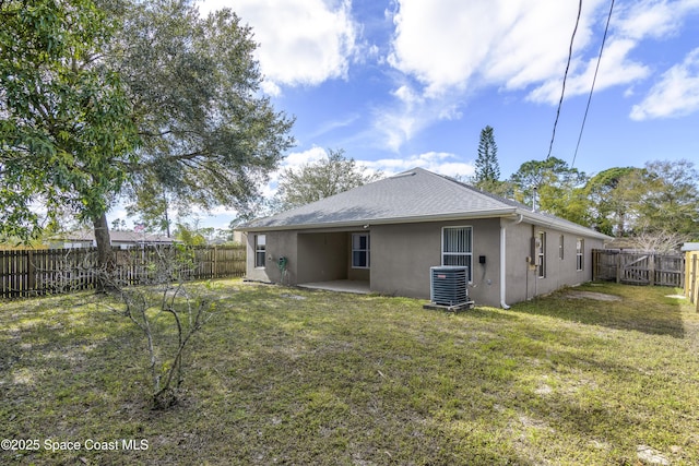 rear view of property with cooling unit and a lawn