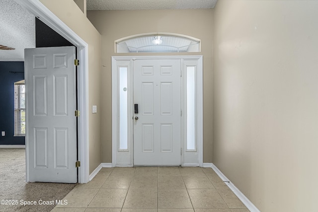 foyer entrance featuring a textured ceiling and light tile patterned flooring