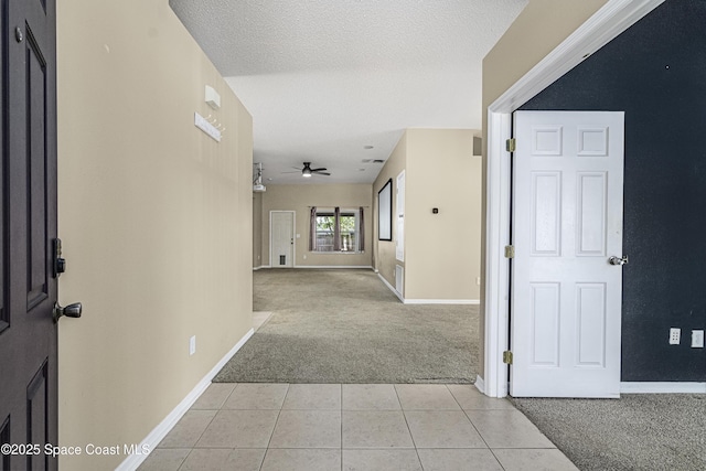 hallway with light colored carpet and a textured ceiling