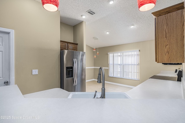 kitchen with lofted ceiling, sink, stainless steel fridge, stove, and decorative light fixtures