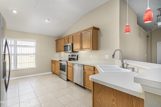 kitchen featuring vaulted ceiling, appliances with stainless steel finishes, decorative light fixtures, sink, and kitchen peninsula