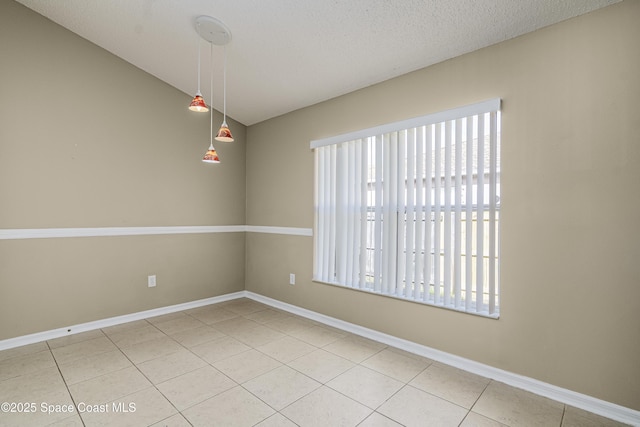 unfurnished room featuring a textured ceiling, vaulted ceiling, tile patterned floors, and a healthy amount of sunlight