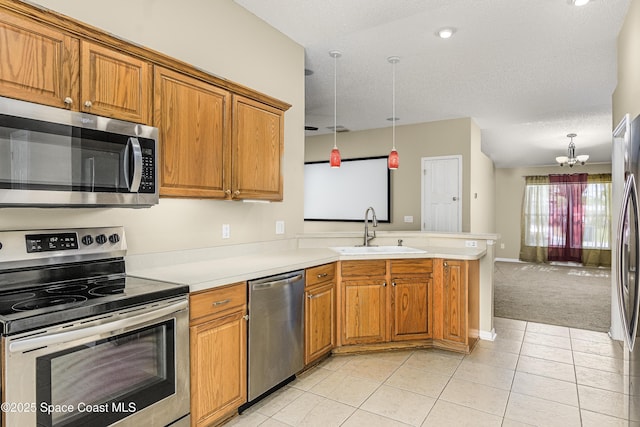 kitchen with sink, light tile patterned floors, stainless steel appliances, decorative light fixtures, and kitchen peninsula