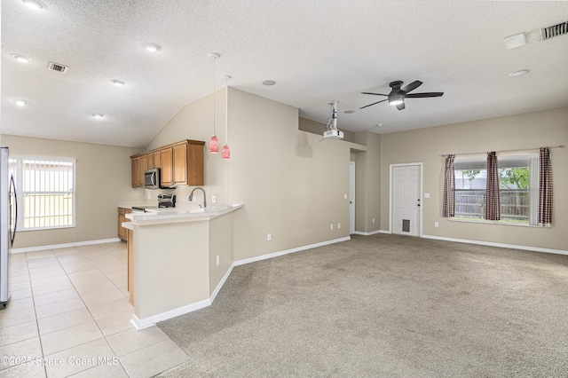 kitchen featuring light tile patterned floors, kitchen peninsula, a healthy amount of sunlight, and appliances with stainless steel finishes