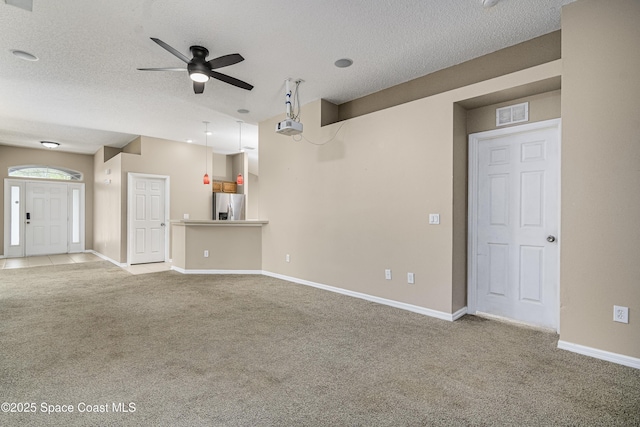 unfurnished living room with ceiling fan, light colored carpet, and a textured ceiling