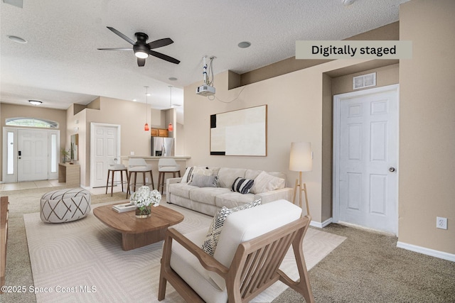 carpeted living room with ceiling fan and a textured ceiling