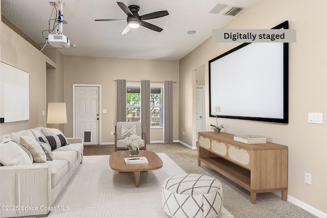 cinema featuring ceiling fan, light colored carpet, and a textured ceiling