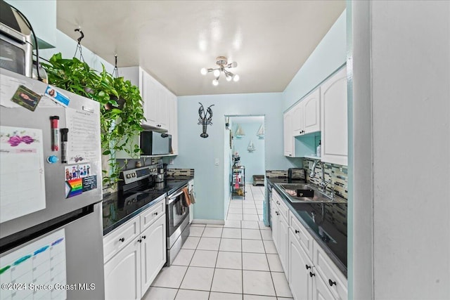 kitchen with appliances with stainless steel finishes, sink, a chandelier, white cabinetry, and light tile patterned flooring