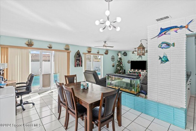 tiled dining room featuring ceiling fan with notable chandelier and a wealth of natural light