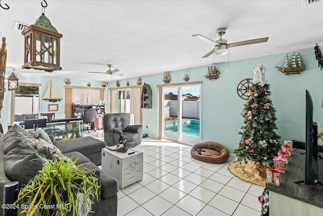 living room featuring ceiling fan, light tile patterned floors, and a textured ceiling