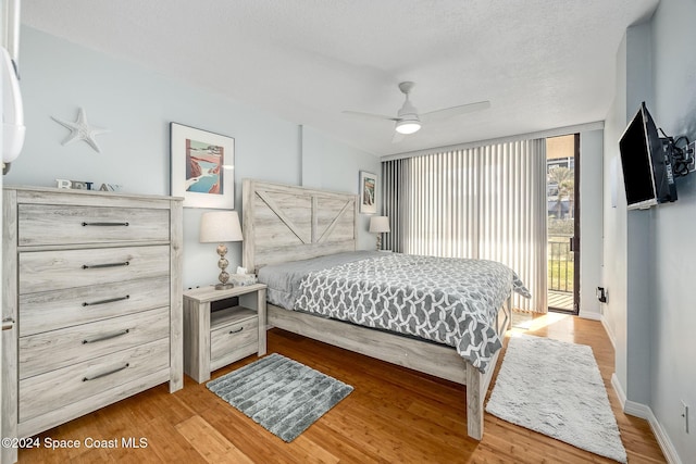 bedroom with hardwood / wood-style flooring, ceiling fan, access to exterior, and a textured ceiling