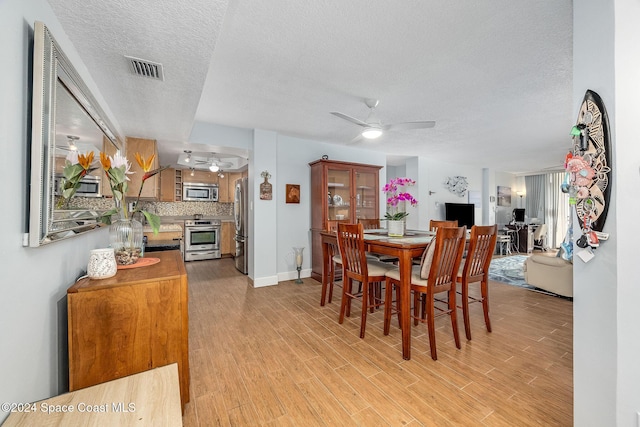 dining area featuring ceiling fan, light hardwood / wood-style flooring, and a textured ceiling