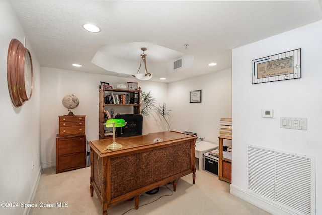 carpeted home office with a textured ceiling and a tray ceiling