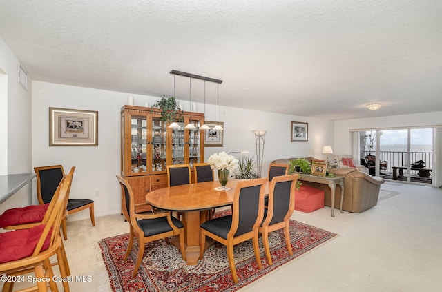 dining area with light carpet and a textured ceiling