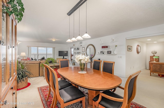 dining space with light colored carpet and a textured ceiling