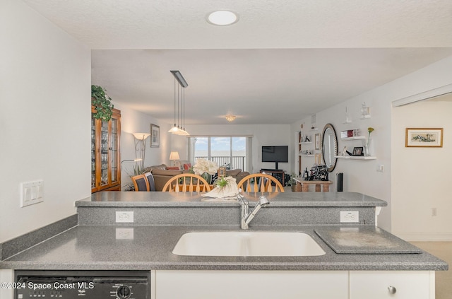 kitchen featuring dishwasher, white cabinets, sink, hanging light fixtures, and a textured ceiling