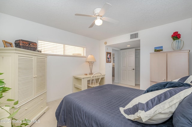 bedroom with a textured ceiling, light colored carpet, and ceiling fan