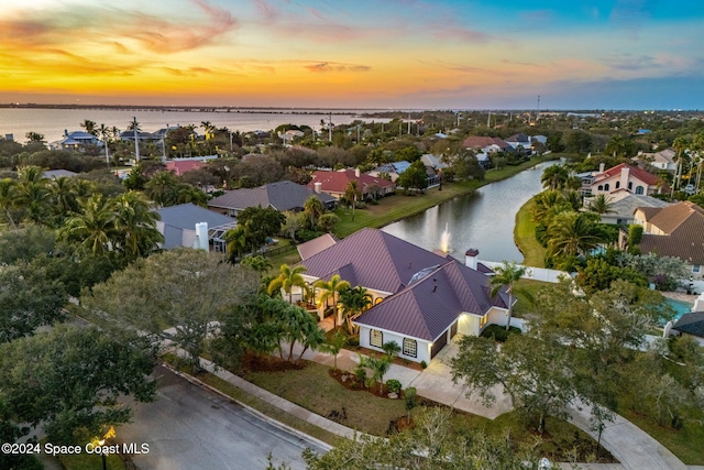 aerial view at dusk featuring a water view