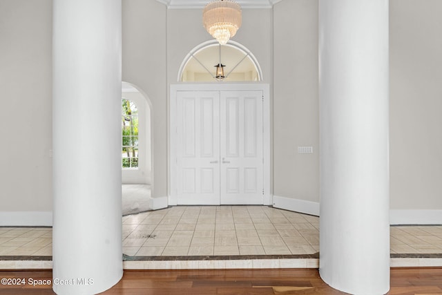 foyer with hardwood / wood-style floors, crown molding, and an inviting chandelier