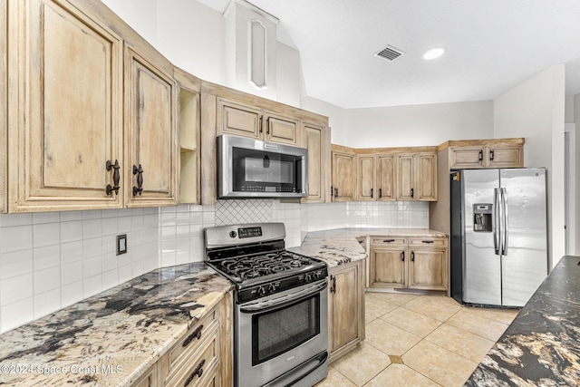 kitchen with decorative backsplash, appliances with stainless steel finishes, and dark stone counters