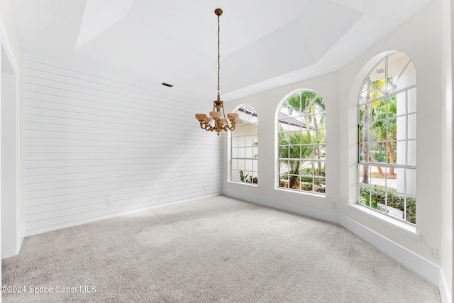 spare room featuring carpet flooring, a wealth of natural light, and a notable chandelier