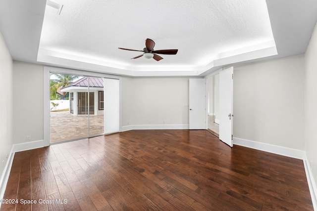 spare room with a raised ceiling, dark hardwood / wood-style flooring, and a textured ceiling