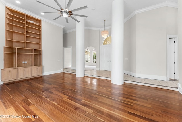 unfurnished living room with ornamental molding, a high ceiling, and hardwood / wood-style flooring