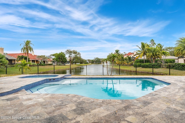 view of pool featuring a patio area, a water view, and an in ground hot tub