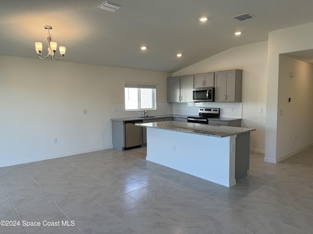 kitchen with appliances with stainless steel finishes, an inviting chandelier, gray cabinets, a kitchen island, and lofted ceiling