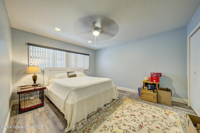 bedroom with ceiling fan, a textured ceiling, and hardwood / wood-style flooring