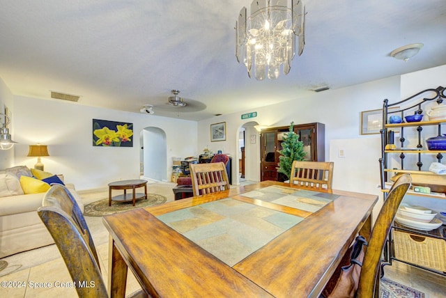 tiled dining room featuring ceiling fan with notable chandelier