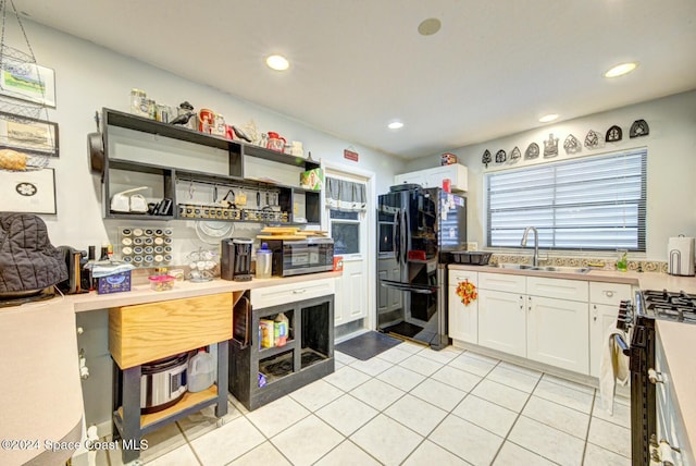 kitchen featuring black fridge with ice dispenser, gas stove, white cabinetry, and sink