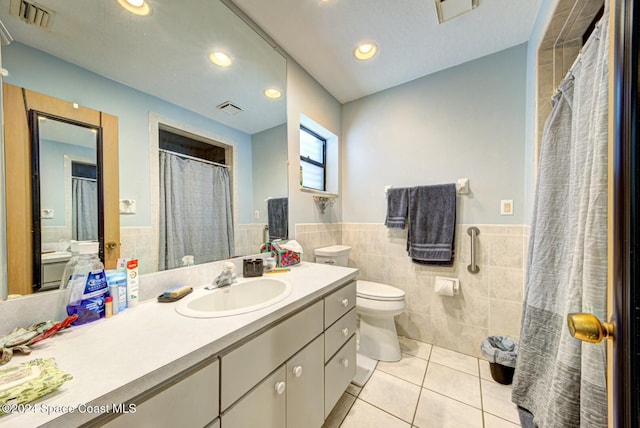 bathroom featuring tile patterned flooring, vanity, tile walls, and toilet